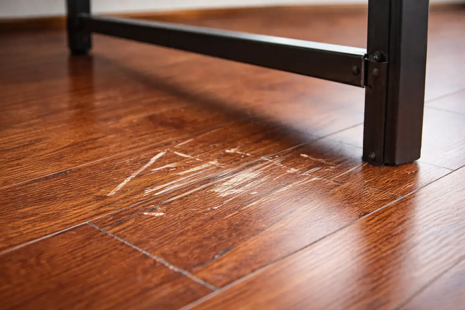 Close-up of a metal bed frame leg scratching a hardwood floor during setup.